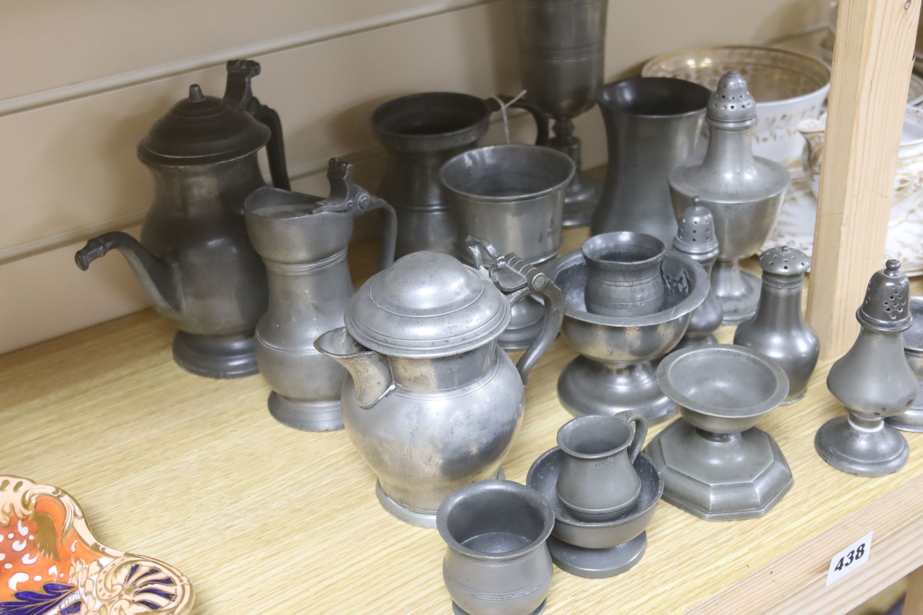 Eighteen items of 18th and 19th century pewter, including lidded jugs, measures, goblets, salt and pepper pots and a chocolate pot